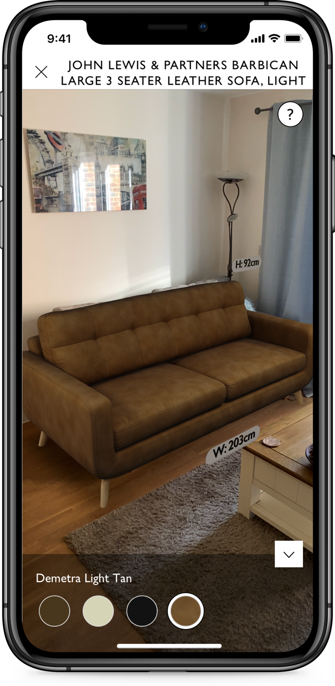 The Virtual Sofa feature on an iPhone: a tan leather three-seater placed by augmented reality in a living room, labelled H: 92cm and W: 203cm, with a row of colour swatches and the shade name Demetra Light Tan beneath it.